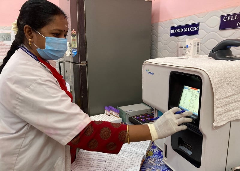 A doctor wearing a mask and gloves using a machine